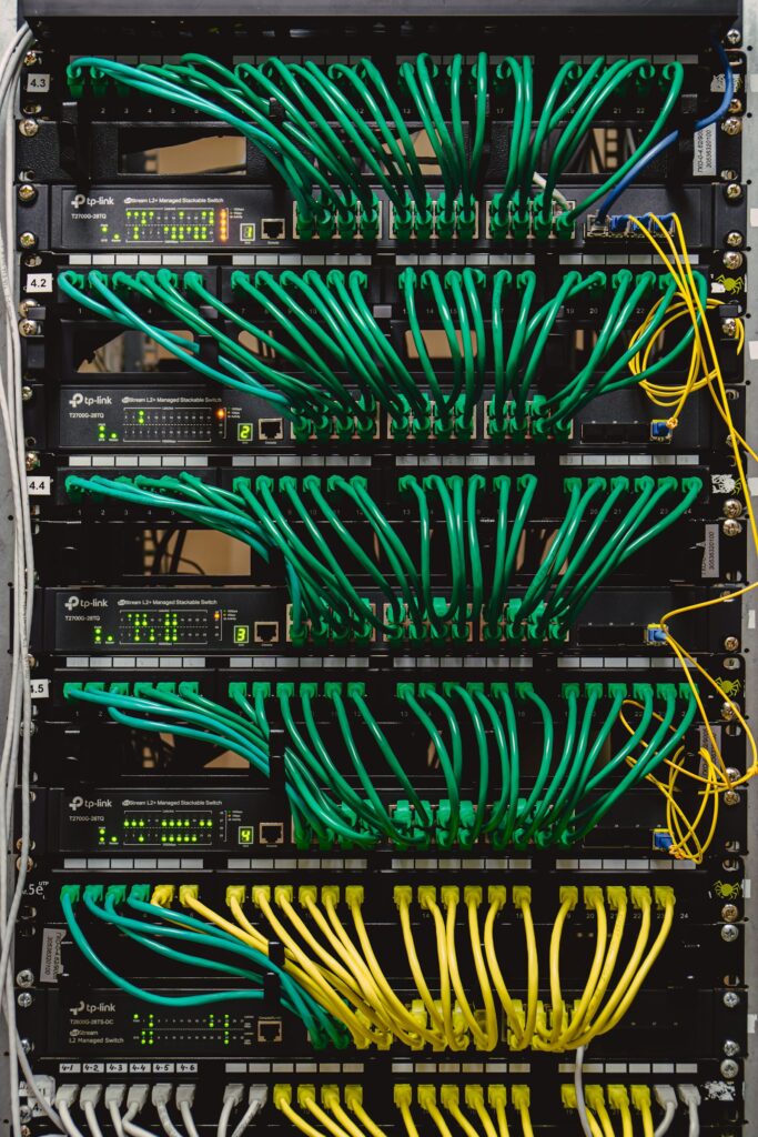 Rack of network switches with green patch cables