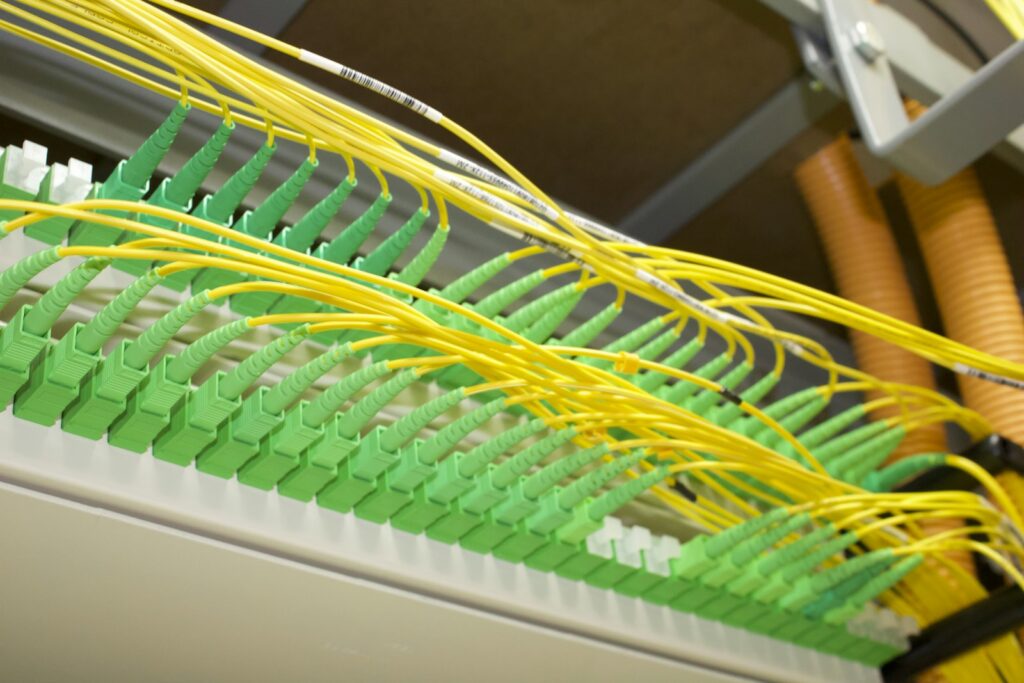 Fiber optic patch panel with green connectors and yellow fiber cables